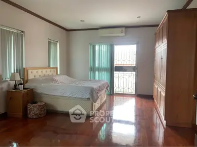 Spacious bedroom with wooden flooring and ample natural light, featuring a large bed and built-in wardrobe.