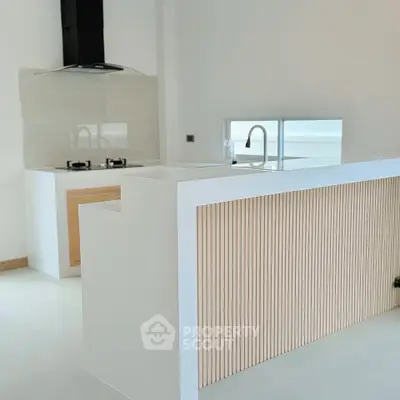Modern kitchen with sleek white countertops and gas stove, featuring a minimalist design and ample natural light.