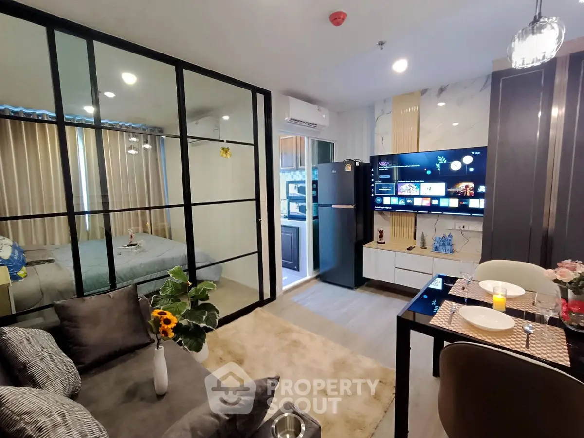 Modern open-plan living room with glass partition, cozy bedroom, and stylish kitchen area.