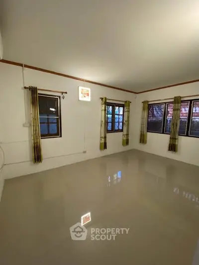 Spacious empty room with large windows and glossy tiled floor, perfect for customization.