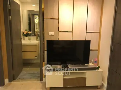 Modern living room with TV and view into a stylish bathroom