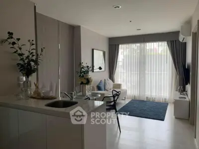 Modern open-layout living room with kitchen, featuring sleek design and natural light.