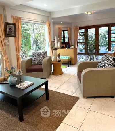 Spacious living room with modern decor and large windows offering garden views.