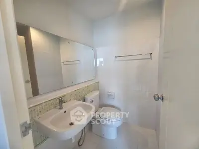 Modern bathroom with sleek fixtures and large mirror in a contemporary home.