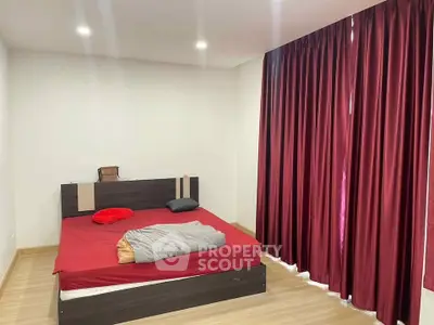 Spacious bedroom with red curtains and modern bed frame, perfect for cozy living.