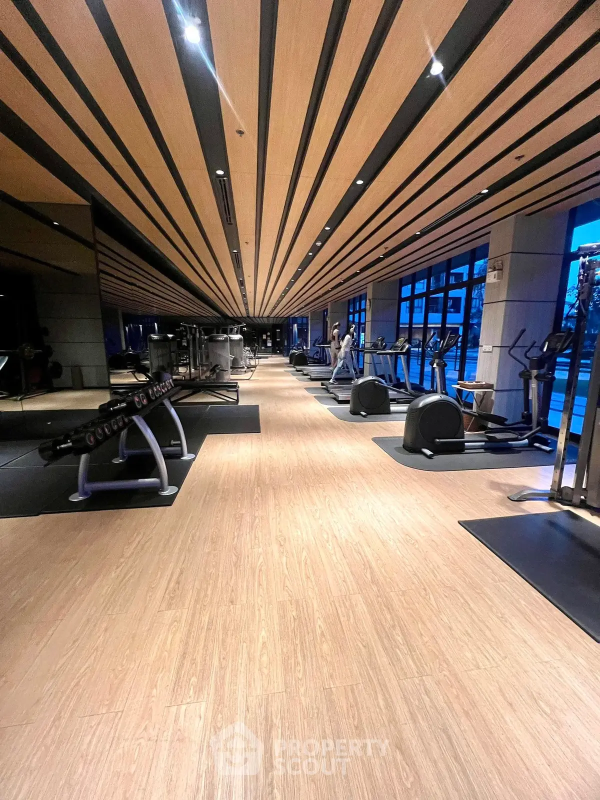 Luxurious modern gym with state-of-the-art equipment and stylish wooden ceiling design.