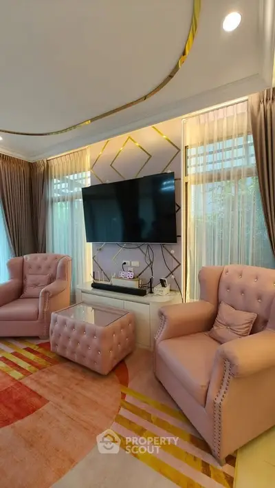 Luxurious living room with elegant pink armchairs, modern TV setup, and stylish decor.