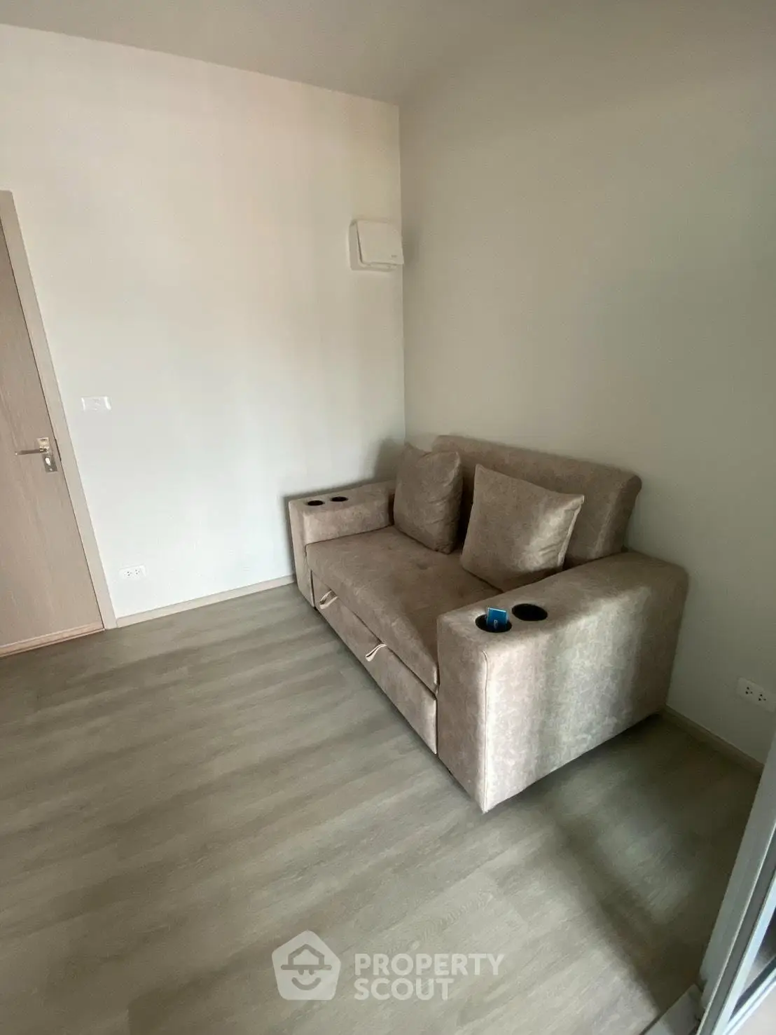 Cozy living room with modern sofa and wooden flooring in a minimalist apartment.