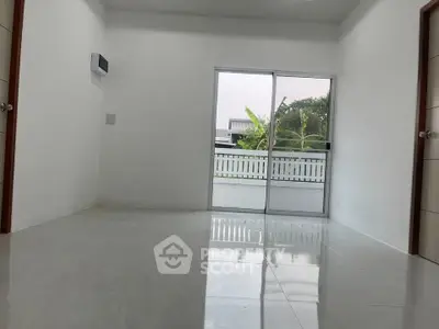 Spacious empty room with sliding glass doors leading to a balcony, offering a serene view.