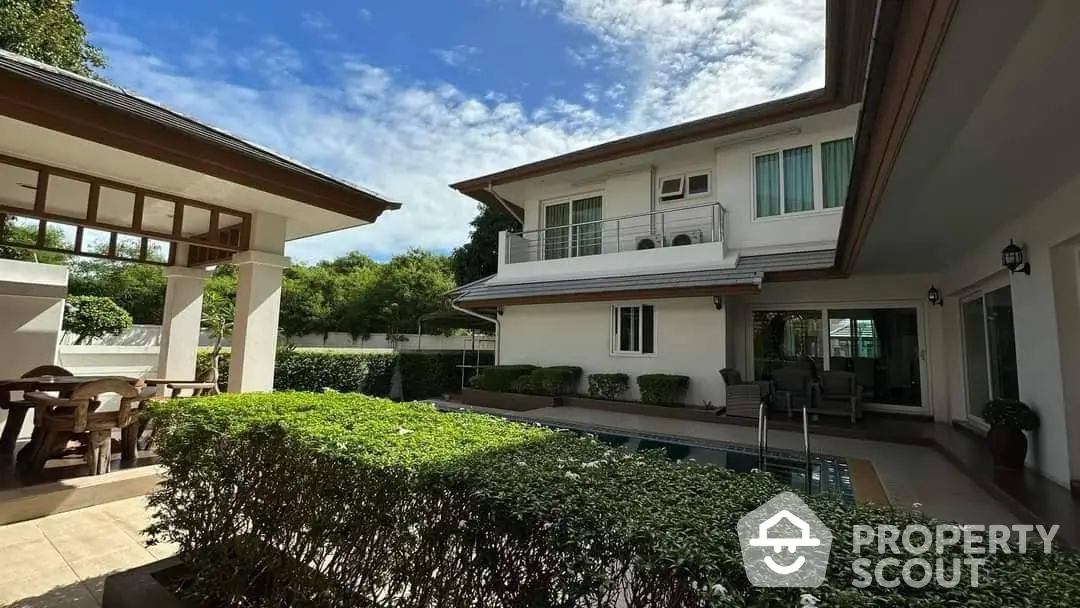 Luxurious two-story residence with a sparkling pool and lush garden, featuring expansive outdoor entertainment space and a serene ambiance.