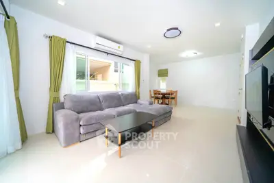 Spacious modern living room with large sofa and dining area, perfect for entertaining.