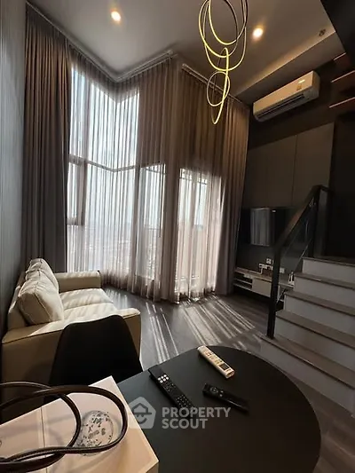 Modern living room with high ceilings, large windows, and stylish lighting in a contemporary apartment.