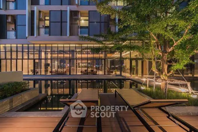 Luxurious modern building exterior with serene water feature and stylish outdoor seating.
