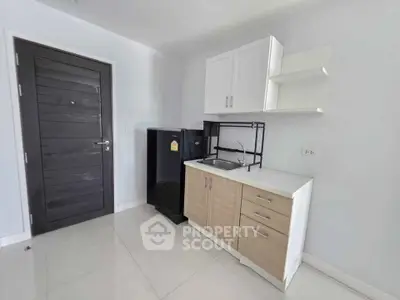 Modern compact kitchen with sleek cabinetry and mini fridge in a bright apartment