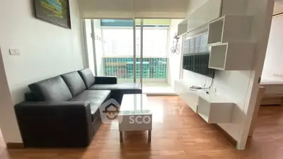 Modern living room with sleek black sofa and glass coffee table, featuring a view of the balcony.