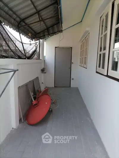 Charming outdoor corridor with satellite dish and tiled flooring, perfect for utility or storage use.