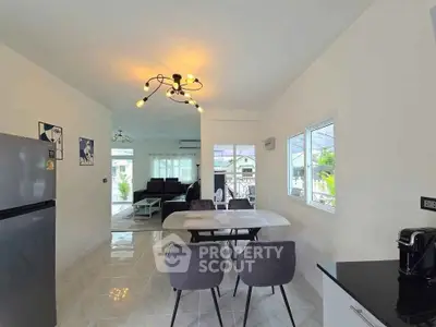 Modern open-plan dining and living area with stylish lighting and large windows.