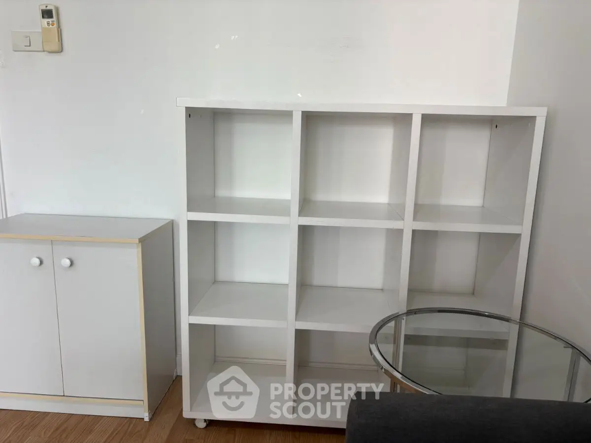 Minimalist interior with white shelving and glass table in modern apartment