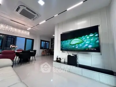 Luxurious modern living room with elegant chandelier and large TV, perfect for entertainment.
