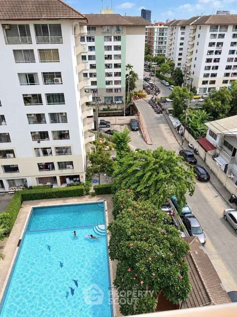 Stunning aerial view of residential complex with pool and lush greenery, perfect for urban living.