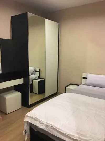 Modern bedroom with sleek furniture and mirrored wardrobe in a cozy apartment.