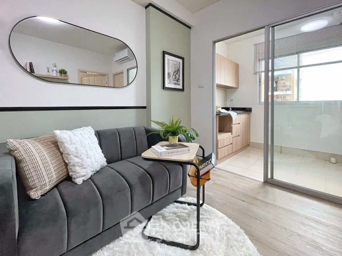 Modern living room with stylish decor and view into a sleek kitchen area.