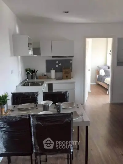 Modern open-layout kitchen with dining area leading to a cozy bedroom, perfect for urban living.