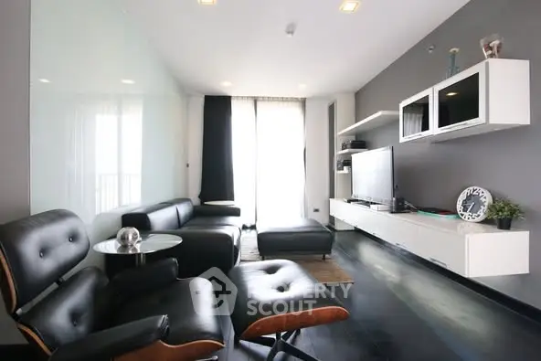 Modern living room with sleek black furniture and wall-mounted TV unit