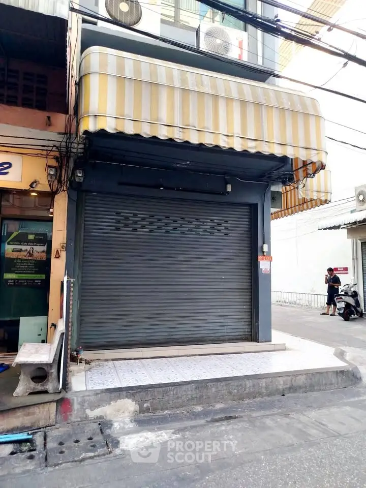 Street view of closed commercial storefront with striped awning