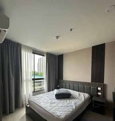 Modern bedroom with large window and stylish decor in urban apartment.