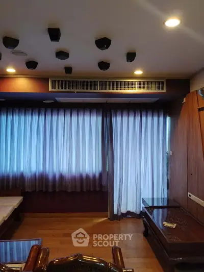 Spacious living room with elegant wooden furniture and large windows with sheer curtains.