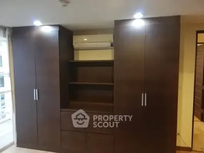 Spacious built-in wooden wardrobe with ample storage and modern lighting in a stylish interior.