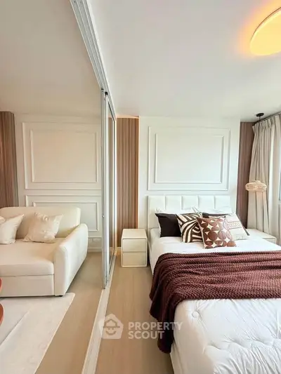 Modern bedroom with elegant decor and cozy seating area, featuring stylish pillows and warm lighting.