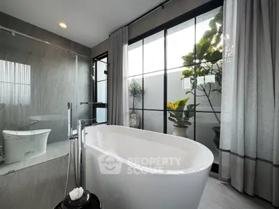 Luxurious bathroom with freestanding bathtub and large window view.