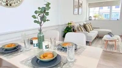 Elegant dining area with cozy living room, modern decor, and natural light