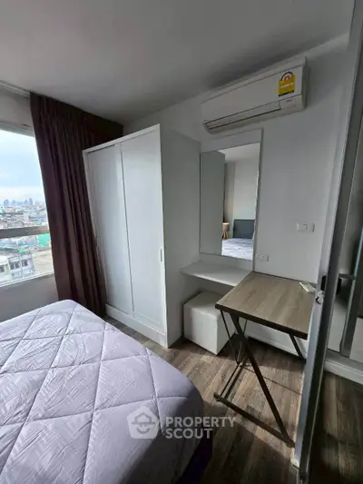 Cozy bedroom with city view, featuring a wardrobe, desk, and air conditioning for modern living.
