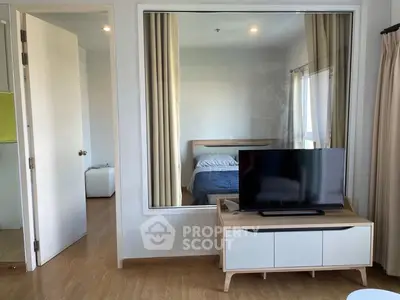 Modern apartment interior with bedroom view through glass partition and stylish TV stand.