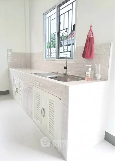 Modern kitchen with sleek white cabinetry and stainless steel sink, perfect for culinary enthusiasts.