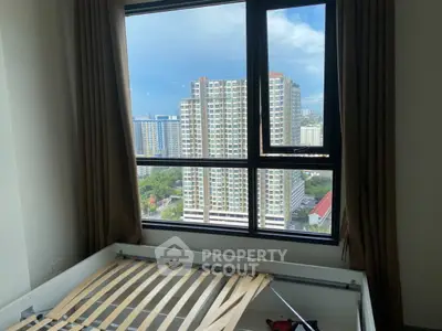 High-rise apartment bedroom with stunning city view through large window.