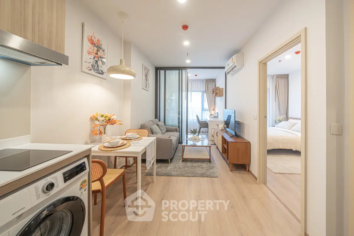 Modern open-plan apartment with stylish kitchen and cozy living area leading to a bright bedroom.