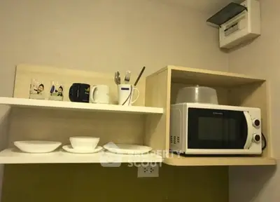 Compact kitchen with microwave and open shelving in modern apartment