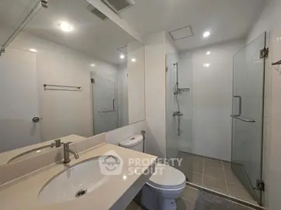 Modern bathroom with glass shower and sleek fixtures in contemporary home.