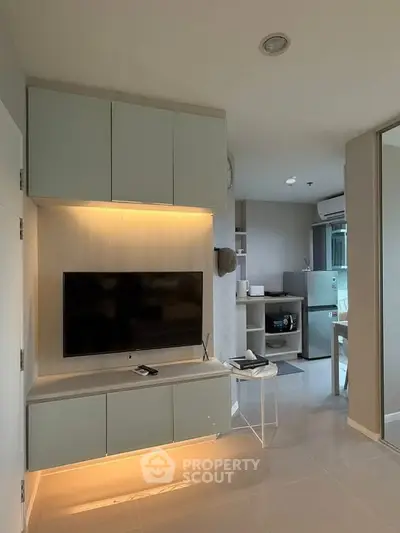 Modern living room with sleek TV setup and open kitchen layout, perfect for contemporary urban living.