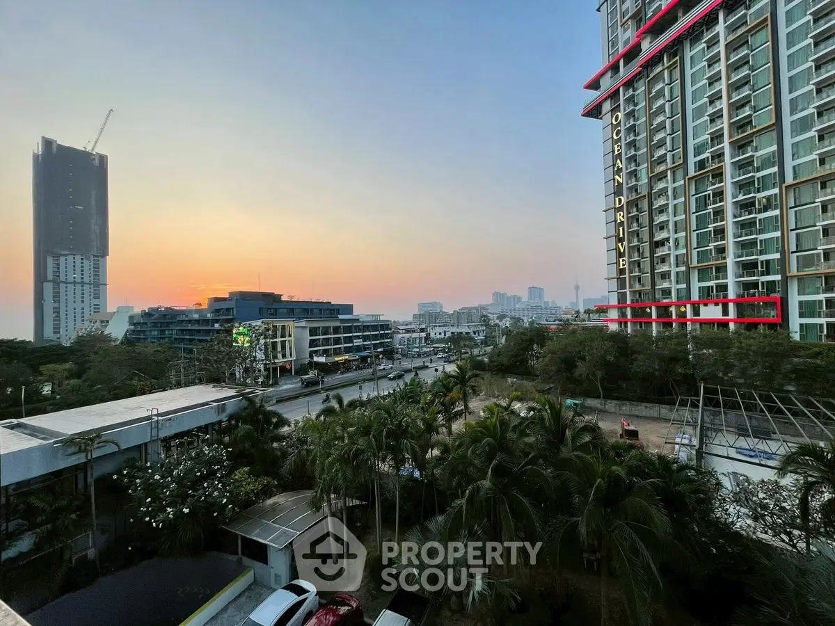 Stunning cityscape view from a high-rise balcony at sunset, showcasing modern architecture and lush greenery.