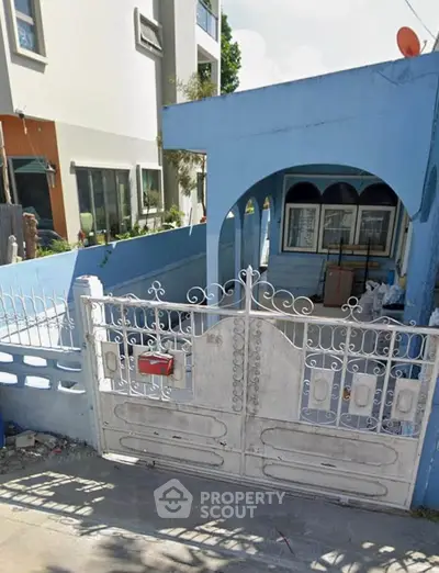 Charming blue exterior with gated entrance and cozy front porch.