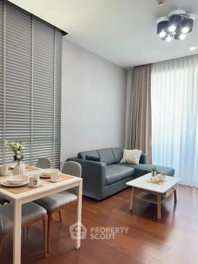 Modern living room with stylish decor and natural light, featuring a cozy sofa and dining area.