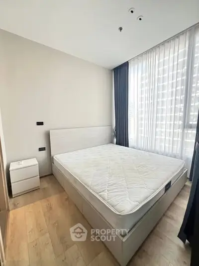 Bright bedroom with large window and modern furnishings in a stylish apartment.