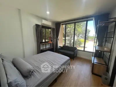 Spacious bedroom with large windows and modern furnishings, offering a serene view of the outdoors.