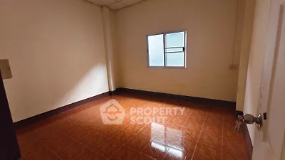 Spacious empty room with tiled floor and window, ideal for customization.