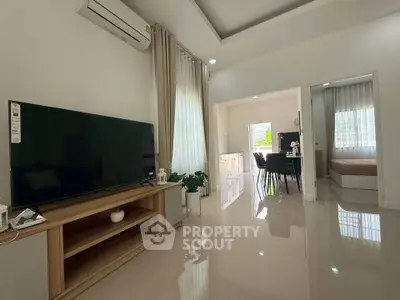 Modern living room with sleek TV and dining area, featuring glossy floors and natural light.
